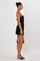 April Seven Kara Dress in black – strapless structured mini dress with welt pocket detail, lined interior, and sculpted fit.