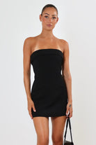 April Seven Kara Dress in black – strapless structured mini dress with welt pocket detail, lined interior, and sculpted fit.