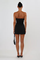 April Seven Kara Dress in black – strapless structured mini dress with welt pocket detail, lined interior, and sculpted fit.