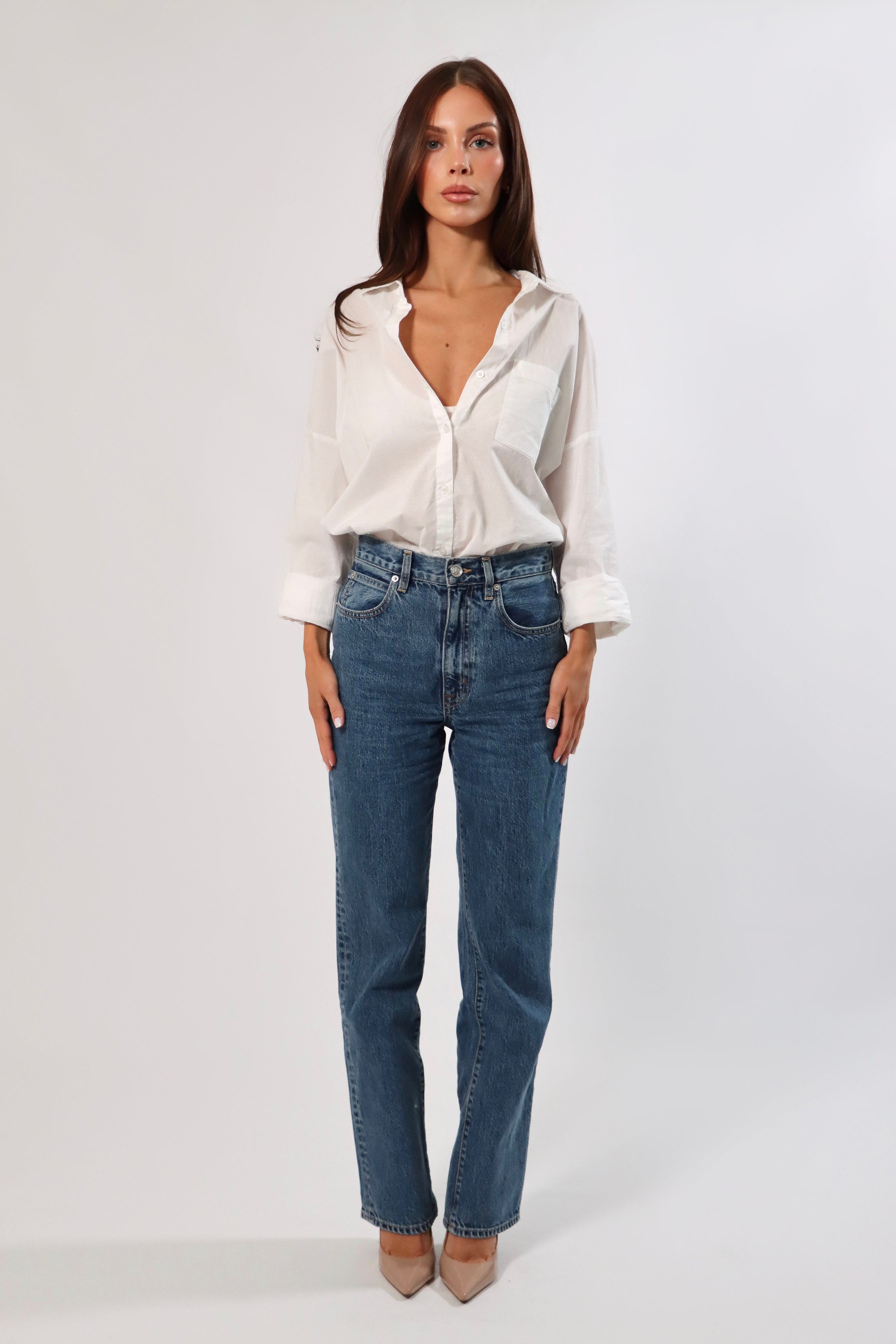 Woman in a white cotton long sleeve pocket shirt and blue jeans.