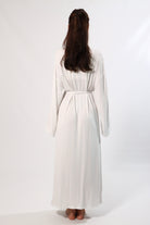 Back view of a woman in a long white robe with bell sleeves and tie waist.