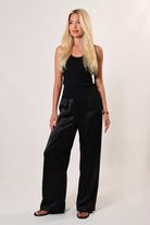 Woman wearing a wide-leg black satin pants on a white studio background
