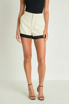 Woman in high-waisted shorts with black satin trim and pockets.