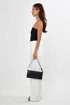 Woman in high-waisted, wide-leg linen pants with button closure and black top.