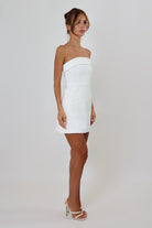 April Seven Kara Dress in white – strapless fitted mini dress with welt pocket detail, structured fabric, and full lining.