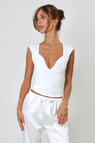 April Seven Beverly Top in white – minimalist fitted top with plunging neckline, cap sleeves, and sculpted silhouette.